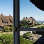 Ansicht durch Fenster auf Dachhäuser und Strand.