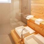 Bad mit Dusche, zwei Waschbecken und Holzbank mit Handtüchern.