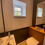 Badezimmer mit Waschbecken, Toilette und kleinem Fenster.