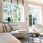 Wohnzimmer mit Sofa, Sessel und Tischen. Fenster und Tür zur Außenterrasse.