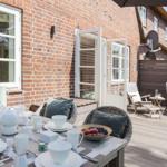Terrasse mit gedecktem Tisch, Sitzgelegenheiten und Blick auf Backsteinhaus.