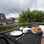 Terrasse mit Tisch, Stühlen und Frühstück. Blick auf Grün und Häuser.
