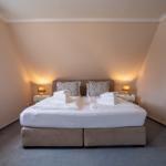 Schlafzimmer mit Doppelbett, zwei Nachttischen und Fenster.