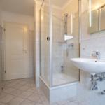 Badezimmer mit Dusche, Waschbecken und Spiegel