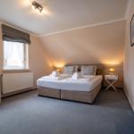Schlafzimmer mit Bett, Nachttisch und Schrank. Fenster mit Rollladen und Heizung.