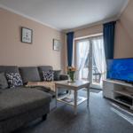 Wohnzimmer mit Sofa, TV und Balkonzugang.