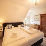 Bedroom with double bed, wooden wardrobe, and bedside table. Window with view outside.