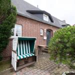 Red brick house with beach chair and green hedge in the front garden.