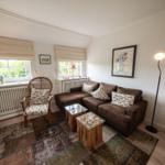 Living room with brown sofa, two tables, and two windows.