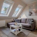 Dachgeschosswohnung mit zwei Dachfenstern, Sofa und Wandbild.