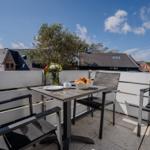 Terrasse mit Tisch, Stühlen und Blick auf Wohnhäuser.