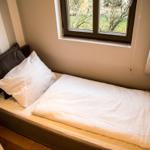 Ein Bett mit weißer Bettwäsche und einem dunklen Kissen unter einem Fenster.