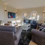 Wohnzimmer mit Sofa, Sesseln, Fernseher und Kamin.