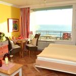 Zimmer mit Bett, Tisch, Stühlen und Meerblick über Balkon