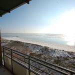 Blick von Balkon auf schneebedeckten Strand und gefrorenes Wasser.