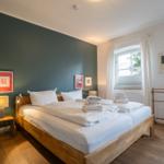 Bedroom with wooden bed, green wall, and window with white curtains.