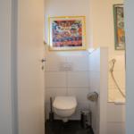 Bathroom with toilet, shower, and wall pictures