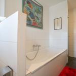 Bath with bathtub, wall art, and red rug