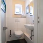 Bathroom with toilet, sink, and mirror. Wall decoration with pictures and window.