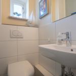 Bathroom with sink, toilet, and window with sailboat model.