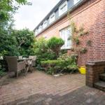 Backyard with table, chairs, plants, and brick wall.