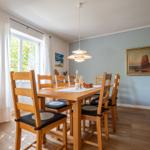 Dining room with wooden table, chairs, and wall paintings.