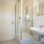 Badezimmer mit Dusche, Waschbecken und Spiegel.