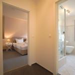 Schlafzimmer mit Bett und Nachttisch. Nebenraum mit Dusche und Toilette.