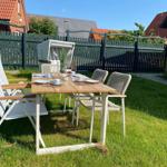 Garten mit Tisch und Stühlen für sechs Personen.
