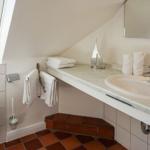 Badezimmer mit Waschbecken, Spiegel und Dachfenster. Terrakottafußboden und Handtücher.