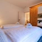 Bedroom with bed, mirrored wardrobe, and towels.