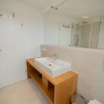 Badezimmer mit Waschbecken, Spiegel und Dusche.