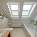 Badezimmer mit Dachfenstern, Badewanne und Toilette.