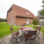 Rotes Ziegelhaus mit Garten und Terrasse mit Tisch und Stühlen.