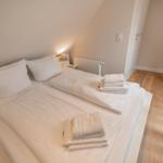 Schlafzimmer mit weißem Bett, gefalteten Handtüchern und Holzboden.