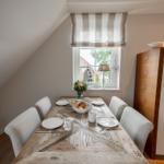 Esszimmer mit Holztisch, Stühlen und Fenster mit Blick nach draußen.