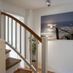 Staircase with wooden handrail and wall picture of a seagull.