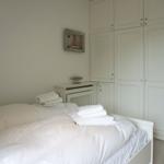 Bedroom with white bed, wardrobe, and wall picture with sailboat.