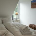 Bedroom with bed, nightstand, and basket. Window with view of green.