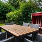 Backyard with wooden table, gray chairs, and red beach chair.