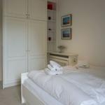 Bedroom with white bed, wardrobe, and wall pictures