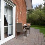 Terrace with table and chairs next to a bedroom with view of greenery.