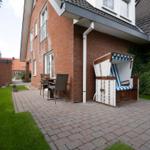 Terrace with beach chair, table and chairs in front of brick house.