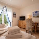 Bedroom with bed, TV, dining table, and garden view.