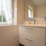 Bathroom with sink, mirror, and window with white curtains.