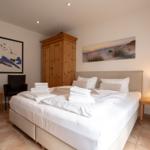 Bedroom with double bed, wooden wardrobe, and wall art.
