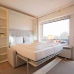 Bedroom with bed, closet, and balcony view.