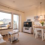 Living and dining area with TV, table, chairs, and view of balcony.