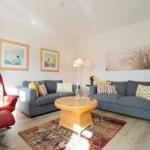 Wohnzimmer mit grauem Sofa, rotem Sessel und runden Couchtisch.