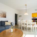 Wohn- und Essbereich mit Sofa, Esstisch und gelber Küche.
